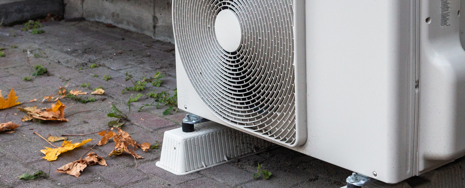 Une pompe à chaleur installée contre la façade d’une maison.